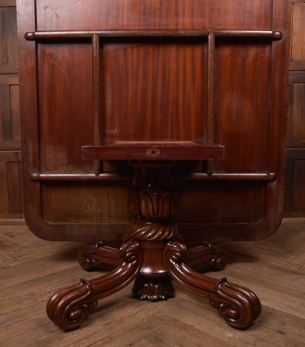 A Victorian mahogany tilt-top table featuring a polished rectangular top with rounded corners set upon a carved pedestal stem with quadruped scrolled legs. View X