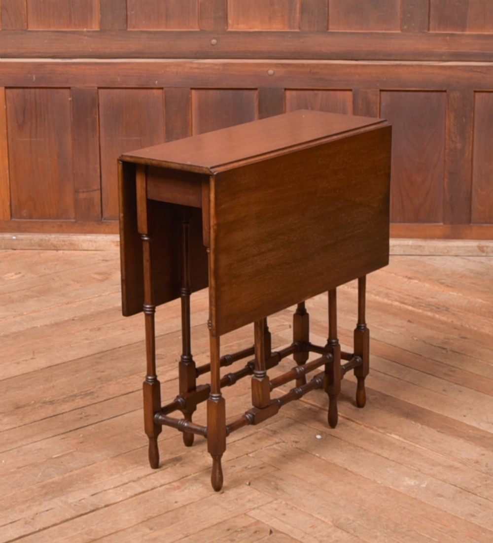 An Edwardian mahogany drop-leaf table with turned legs and lower stretchers, pictured with both leaves folded down.