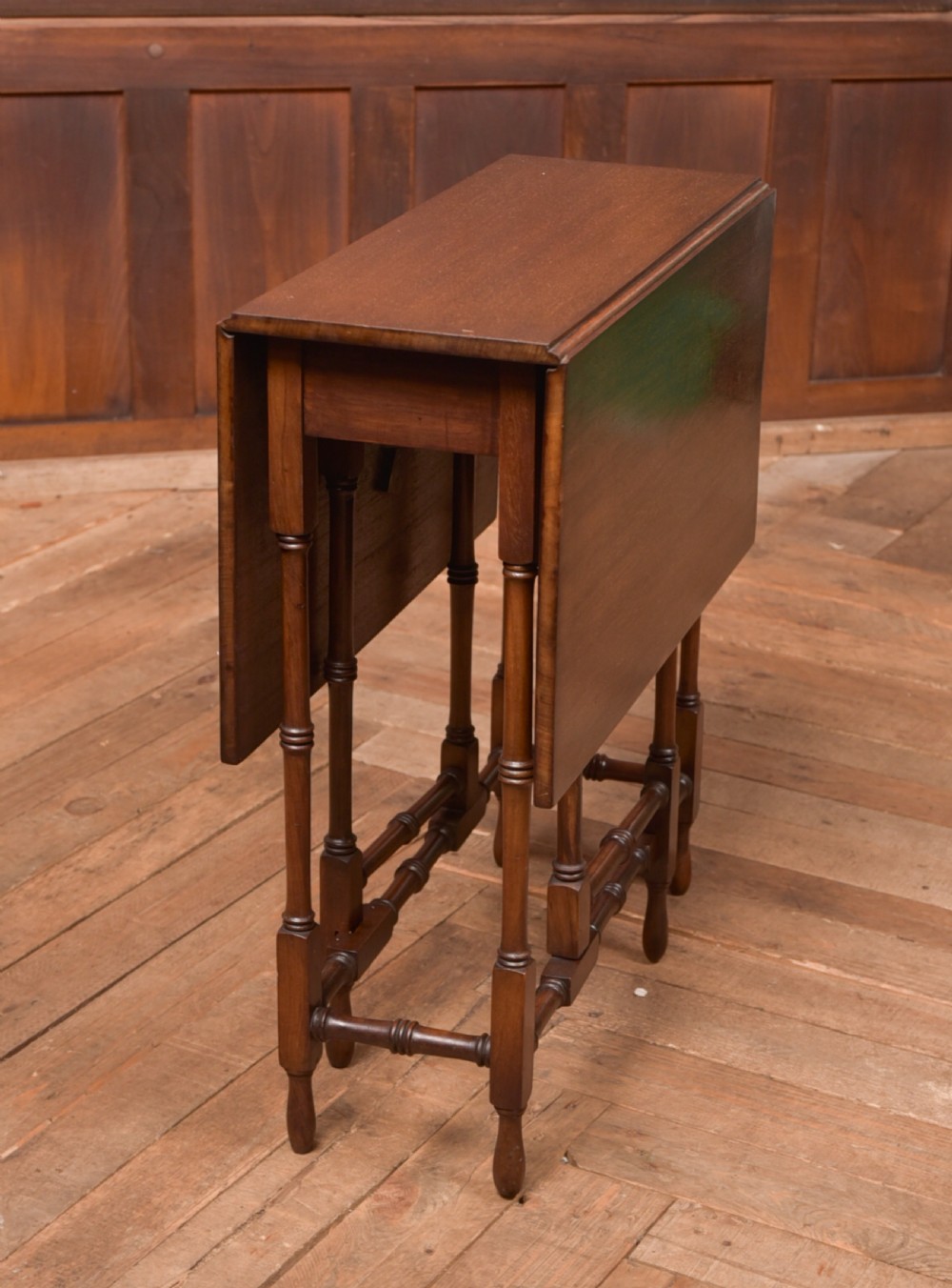 An Edwardian mahogany drop-leaf table with turned legs and lower stretchers, pictured with both leaves folded down. View II