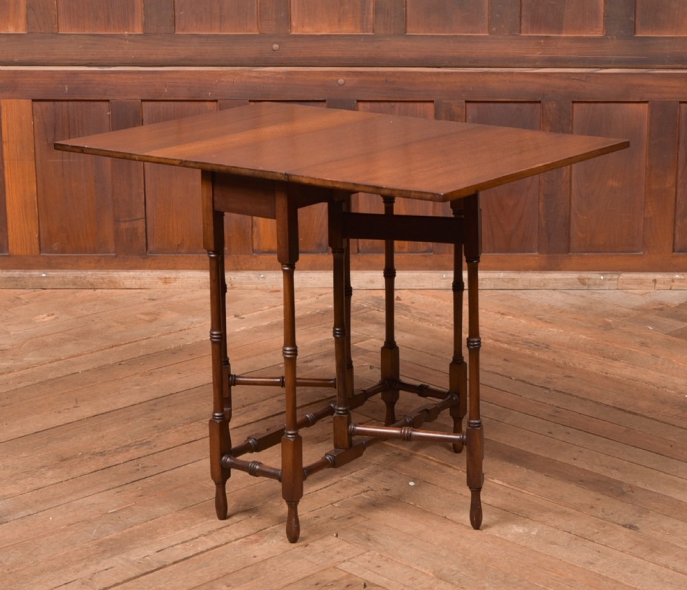 An Edwardian mahogany drop-leaf table with turned legs and lower stretchers, pictured with both leaves folded down. View III
