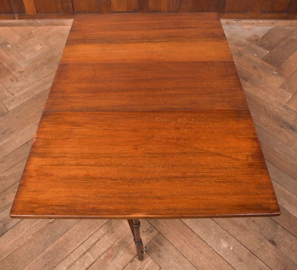 An Edwardian mahogany drop-leaf table with turned legs and lower stretchers, pictured with both leaves folded down. View VI