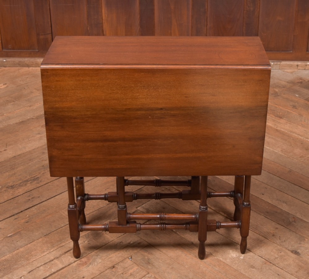 An Edwardian mahogany drop-leaf table with turned legs and lower stretchers, pictured with both leaves folded down. View VII