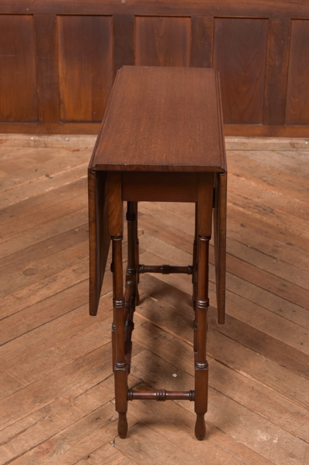 An Edwardian mahogany drop-leaf table with turned legs and lower stretchers, pictured with both leaves folded down. View VIII