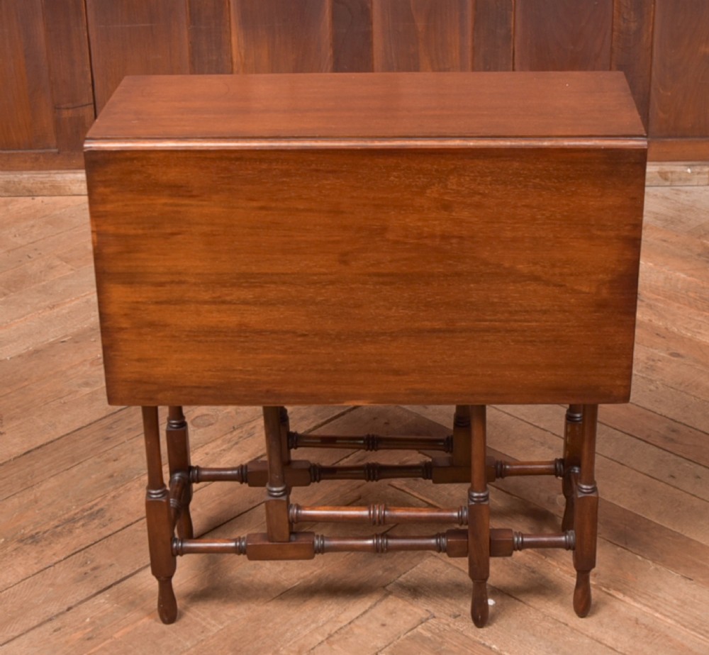 An Edwardian mahogany drop-leaf table with turned legs and lower stretchers, pictured with both leaves folded down. View IX