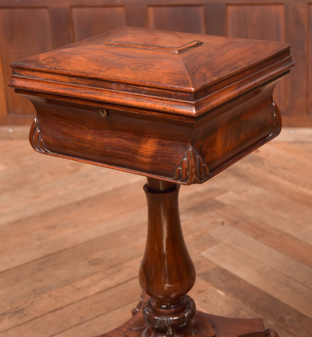 A Victorian rosewood work table featuring a hinged sarcophagus lid, a turned pedestal column, and a carved quadruped base on brass castors. View II