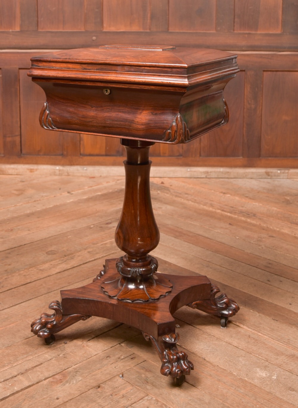 A Victorian rosewood work table featuring a hinged sarcophagus lid, a turned pedestal column, and a carved quadruped base on brass castors. View III