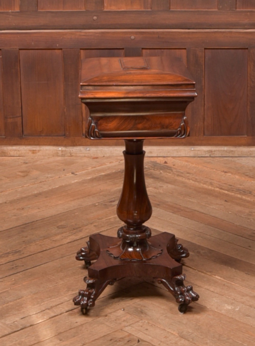 A Victorian rosewood work table featuring a hinged sarcophagus lid, a turned pedestal column, and a carved quadruped base on brass castors. View VIII
