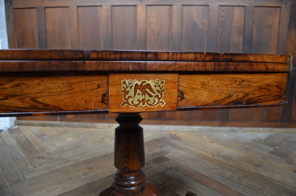 A Regency rosewood card table featuring brass marquetry inlay, a turned pedestal column, and four splayed legs with brass castors. View III