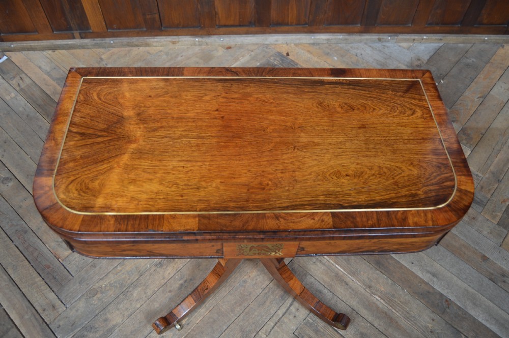 A Regency rosewood card table featuring brass marquetry inlay, a turned pedestal column, and four splayed legs with brass castors. View XIV