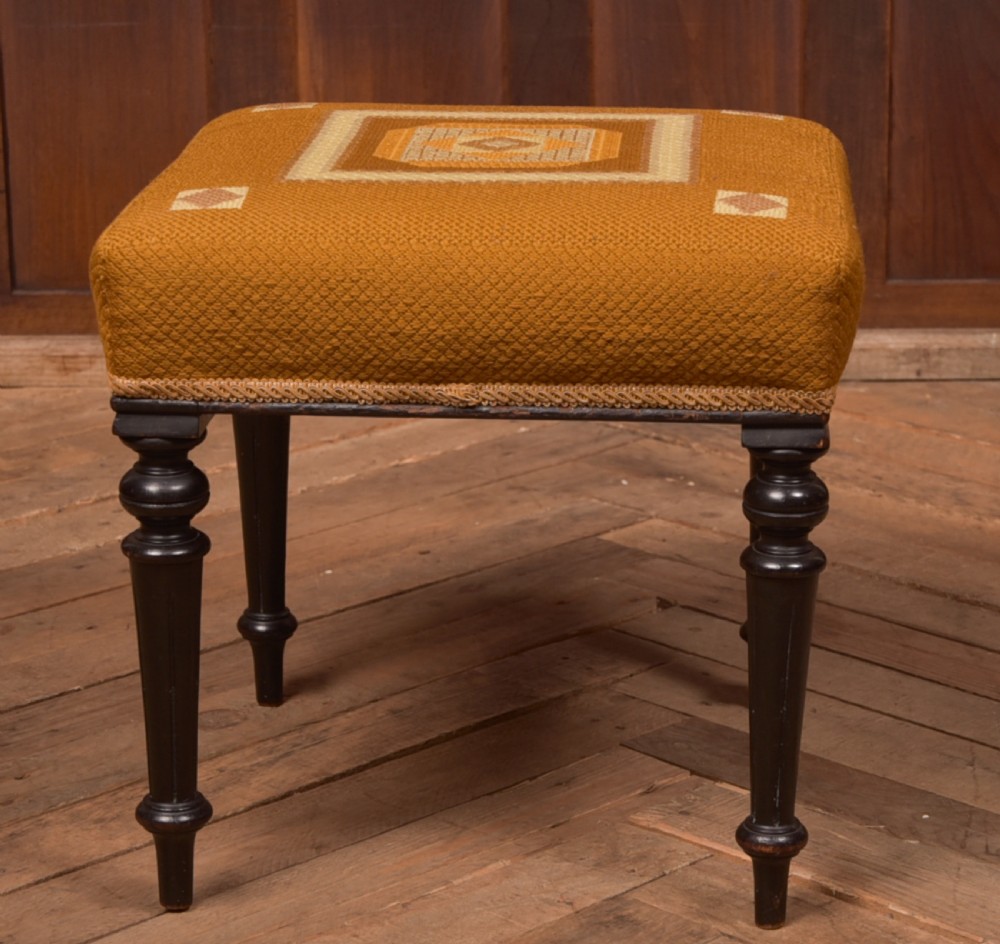 A Victorian rectangular footstool featuring black turned ebonised legs and an ochre yellow geometric needlepoint upholstered top. View III