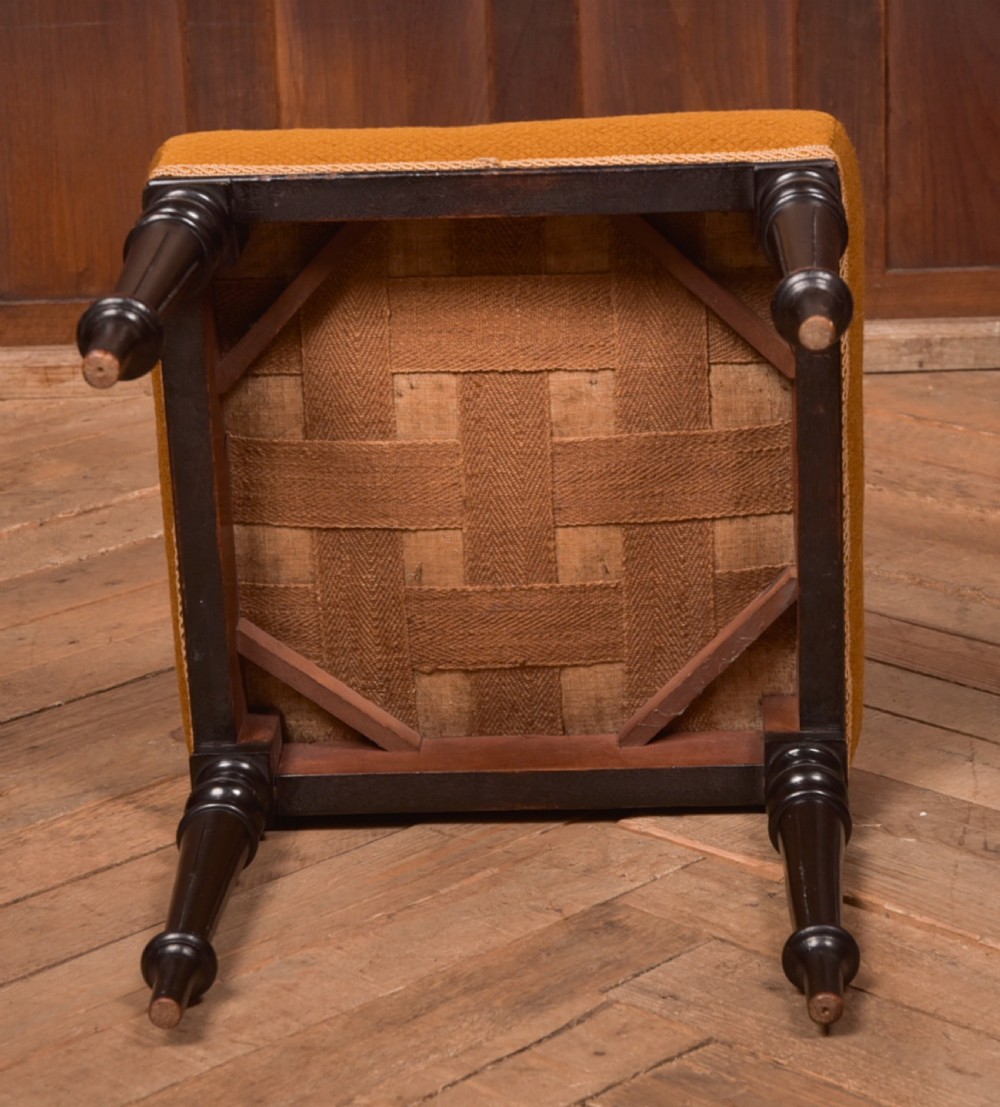 A Victorian rectangular footstool featuring black turned ebonised legs and an ochre yellow geometric needlepoint upholstered top. View VII