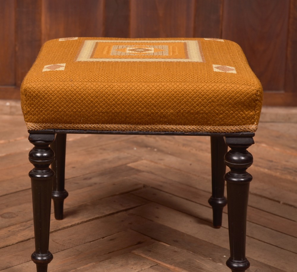 A Victorian rectangular footstool featuring black turned ebonised legs and an ochre yellow geometric needlepoint upholstered top. View VIII
