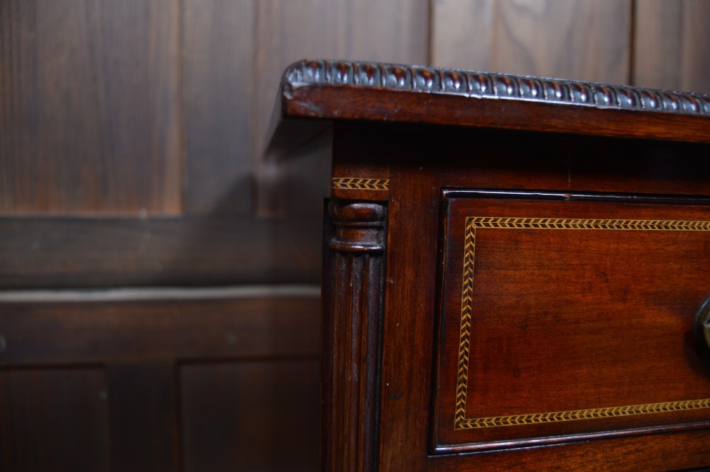 An Edwardian mahogany chest of drawers featuring two short over three long drawers with boxwood stringing inlay, brass oval drop handles, and bracket feet. View XXVI