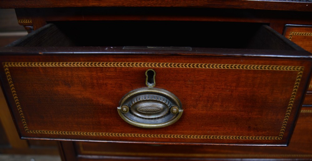 An Edwardian mahogany chest of drawers featuring two short over three long drawers with boxwood stringing inlay, brass oval drop handles, and bracket feet. View XXVII