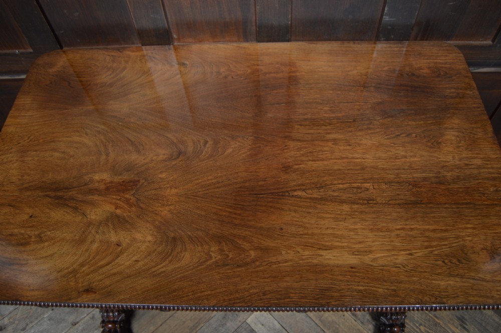 A William IV dark rosewood library side table featuring two frieze drawers with wooden knobs, beaded edge details, turned column supports, and carved claw feet. View VII