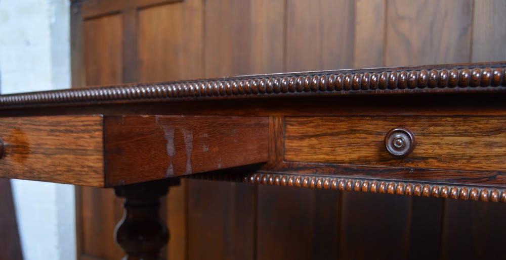 A William IV dark rosewood library side table featuring two frieze drawers with wooden knobs, beaded edge details, turned column supports, and carved claw feet. View XX