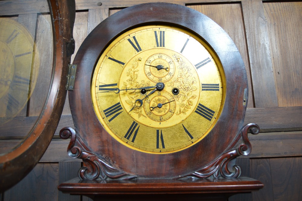 A nineteenth-century Scottish drum head longcase clock crafted from flame mahogany with an ornate circular brass dial. View VII