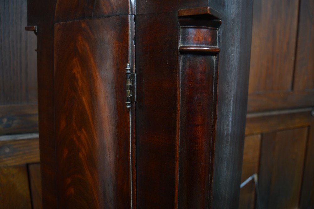 A nineteenth-century Scottish drum head longcase clock crafted from flame mahogany with an ornate circular brass dial. View XVII