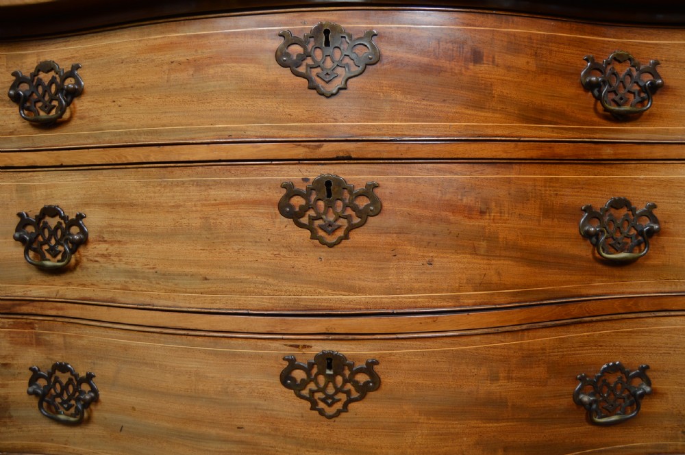A Georgian serpentine-fronted mahogany chest featuring four graduated drawers with brass handles and inlaid border detailing. View VII