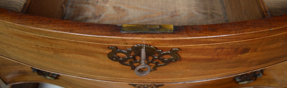A Georgian serpentine-fronted mahogany chest featuring four graduated drawers with brass handles and inlaid border detailing. View XI