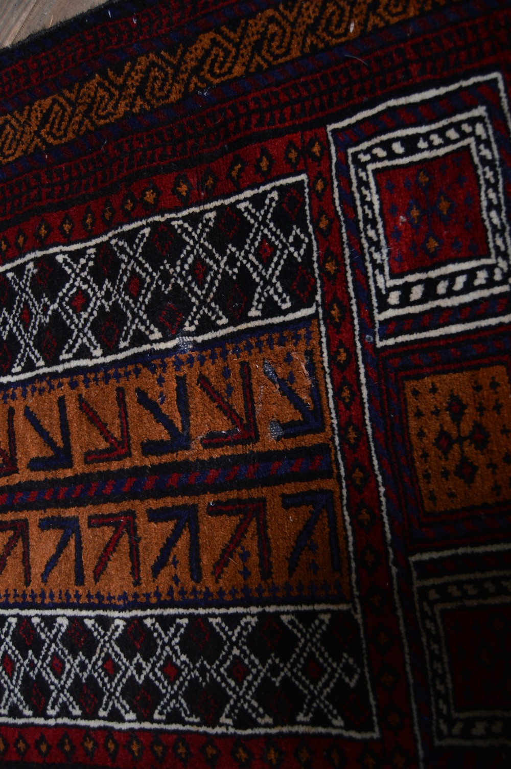 A hand-woven Belouch wool prayer rug featuring a central ochre mihrab motif surrounded by dark red and geometric patterned borders. View IV