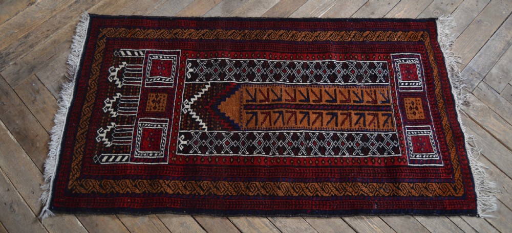 A hand-woven Belouch wool prayer rug featuring a central ochre mihrab motif surrounded by dark red and geometric patterned borders. View VII