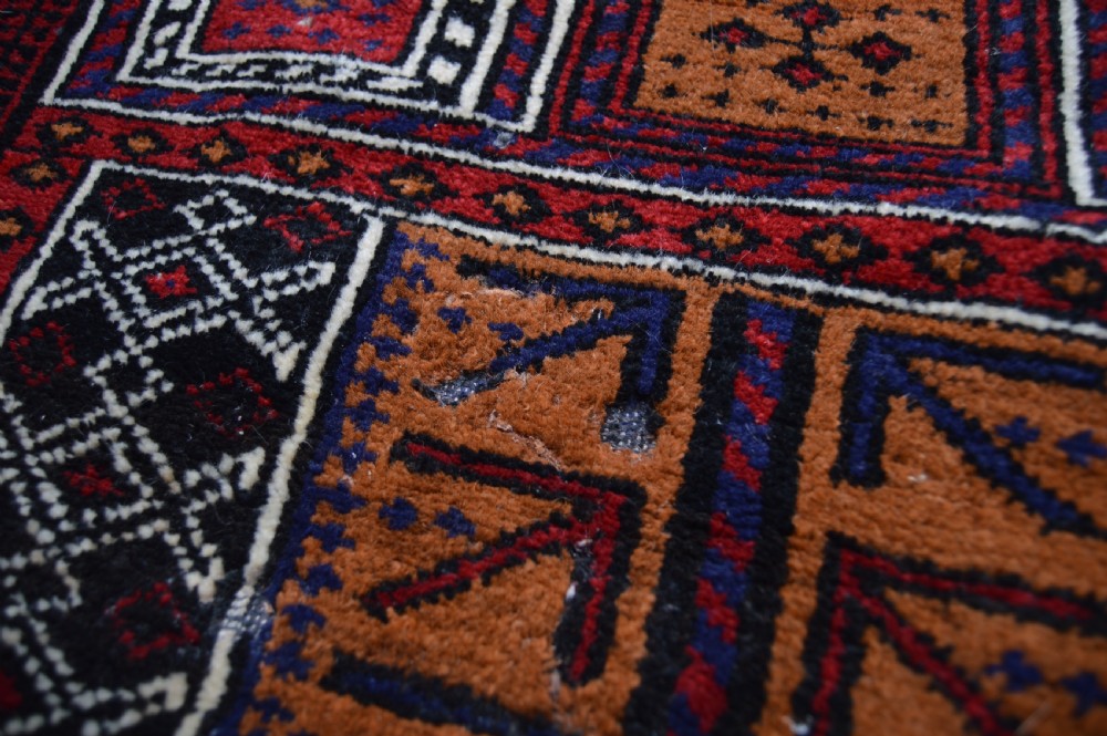 A hand-woven Belouch wool prayer rug featuring a central ochre mihrab motif surrounded by dark red and geometric patterned borders. View IX