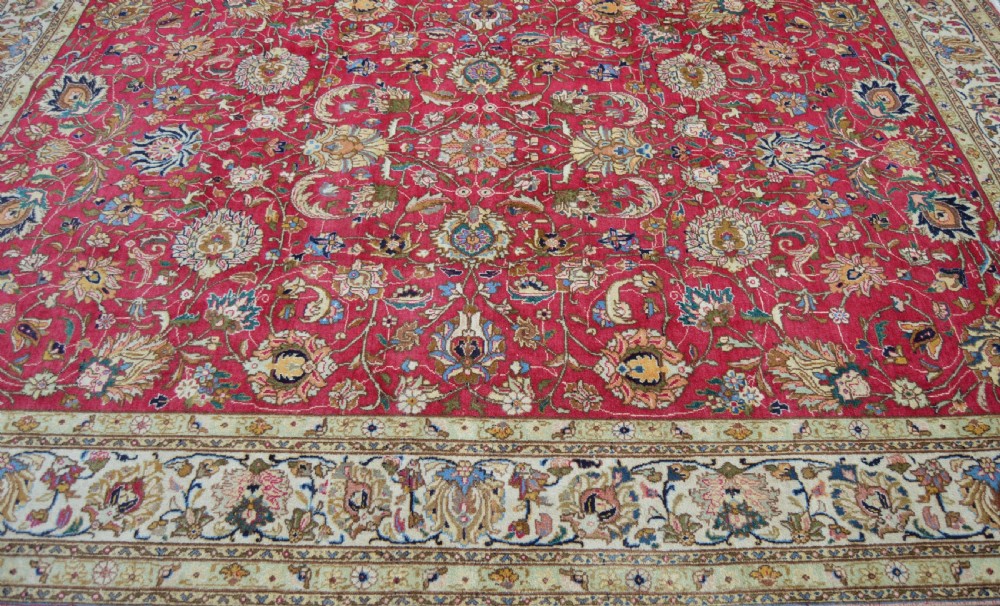 A rectangular handmade Persian wool rug featuring an intricate all-over floral pattern with a dominant red centre and cream borders. View II