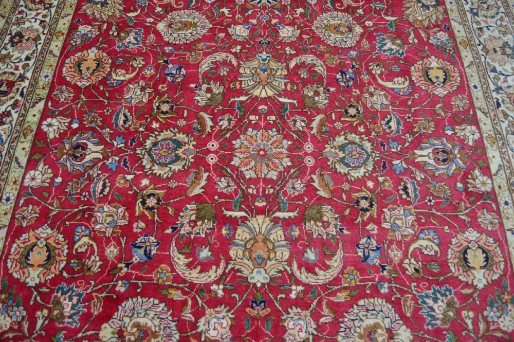 A rectangular handmade Persian wool rug featuring an intricate all-over floral pattern with a dominant red centre and cream borders. View XIII