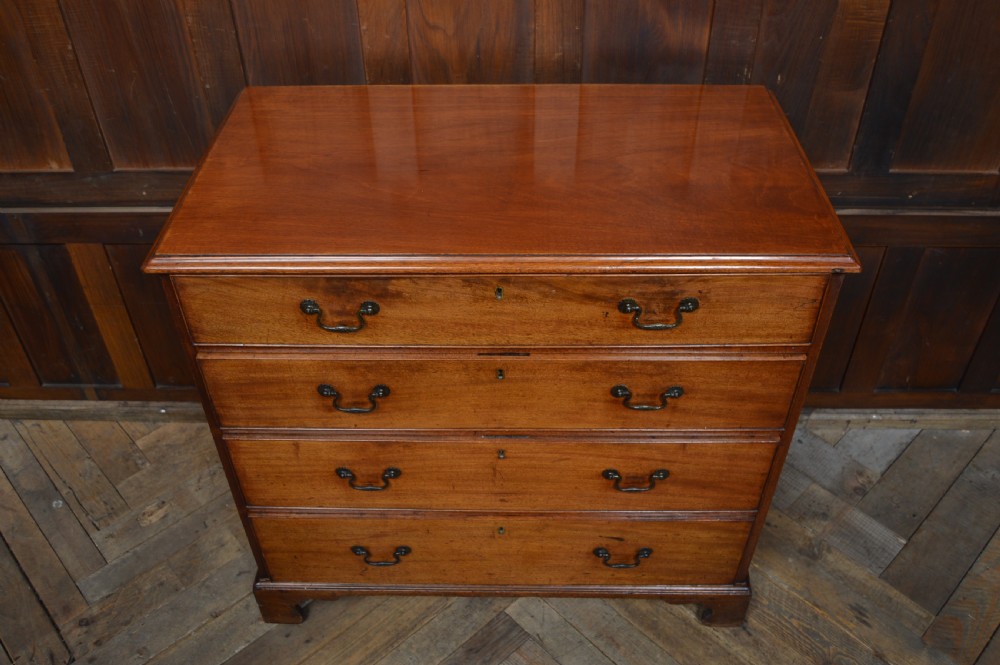 A Regency mahogany chest of drawers featuring four graduated drawers with dark metal handles and classic bracket feet. View V