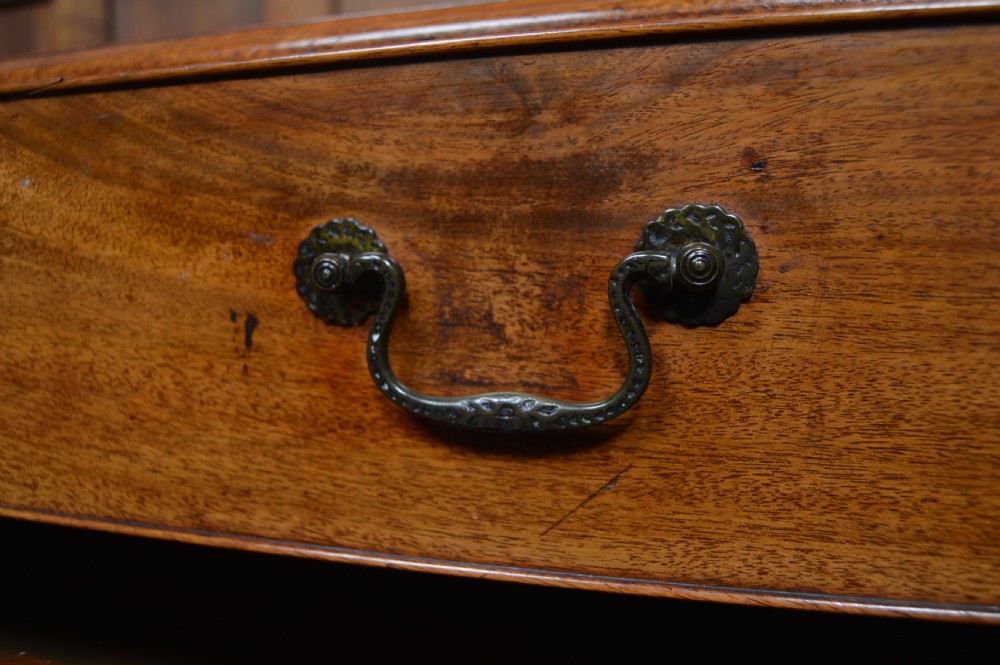A Regency mahogany chest of drawers featuring four graduated drawers with dark metal handles and classic bracket feet. View VI