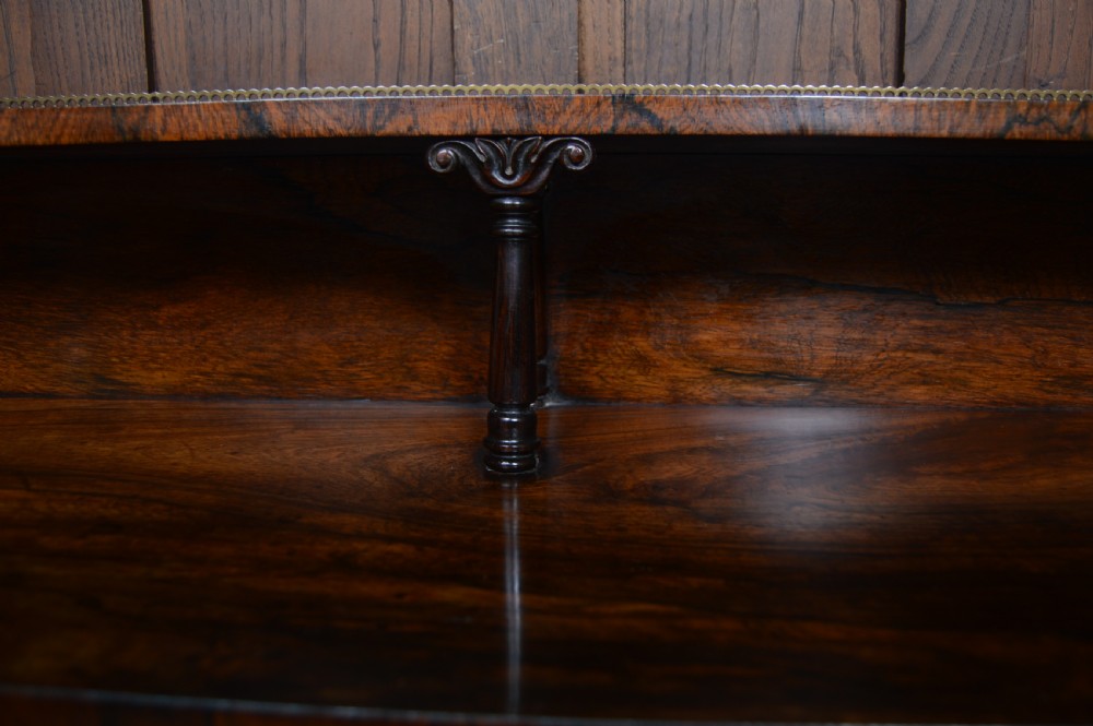An antique dark rosewood low breakfront bookcase featuring open side shelving, a central door with a brass wire mesh grille, and a raised upper tier topped with a brass gallery. View IX