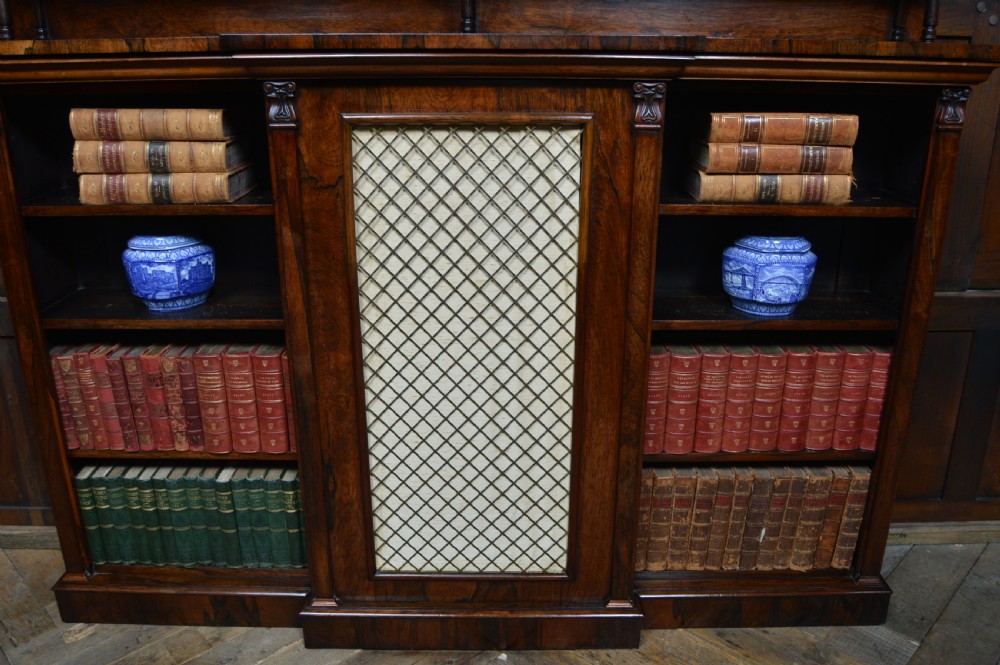 An antique dark rosewood low breakfront bookcase featuring open side shelving, a central door with a brass wire mesh grille, and a raised upper tier topped with a brass gallery. View XII