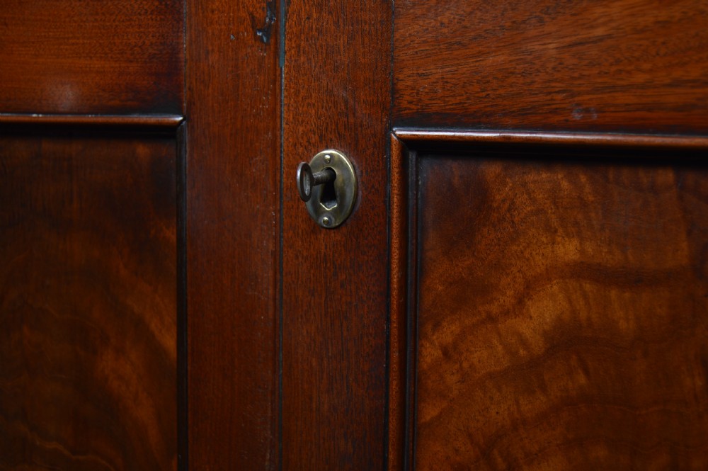 A tall freestanding Georgian corner cabinet made from mahogany featuring flame grain wood door panels and a moulded top cornice. View II
