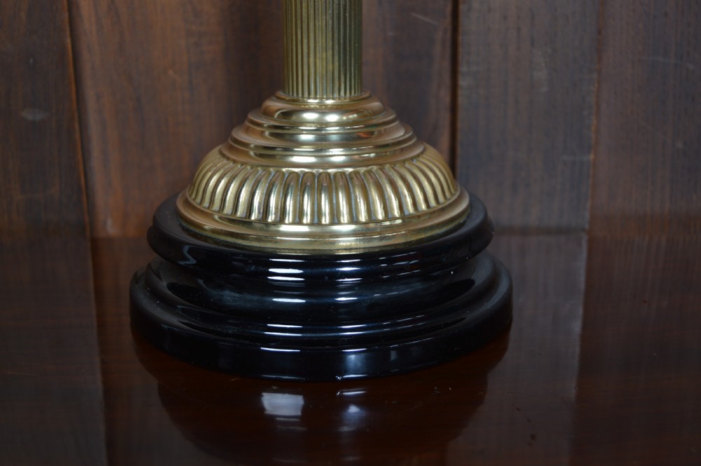 A Victorian brass oil lamp with a black base, fluted column, pink patterned glass reservoir, and frosted glass globe shade with etched detail. View II