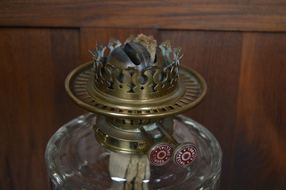 An antique brass paraffin oil lamp featuring a reeded central column, clear glass reservoir, etched frilled glass shade, and clear glass chimney. View X