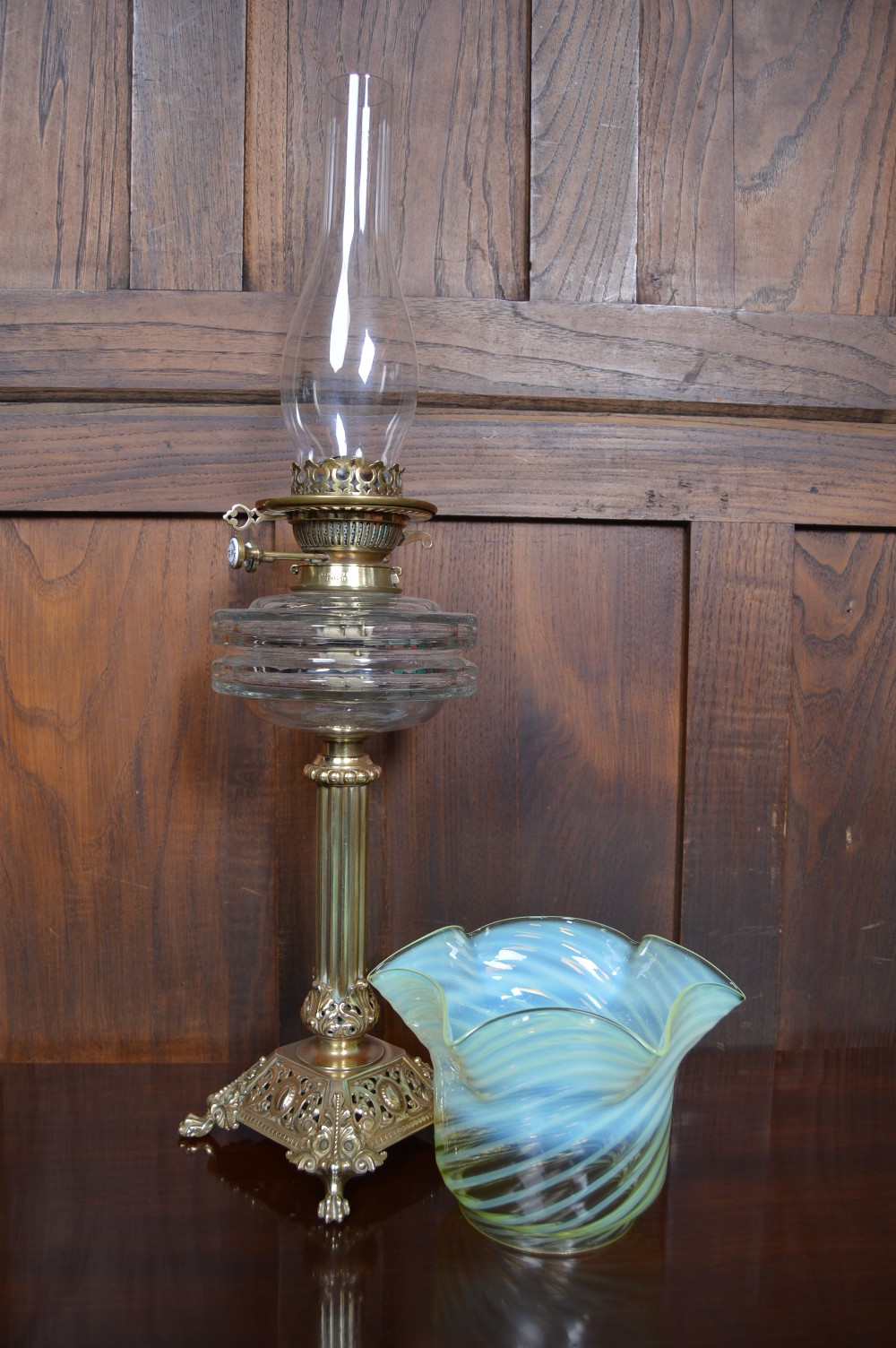 A Victorian brass oil lamp featuring a fluted column base, a clear glass reservoir, a light green swirl opalescent shade, and a tall glass chimney. View IX