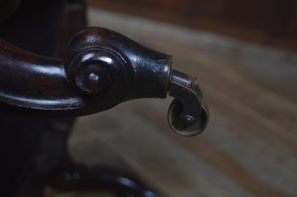 A Victorian low footstool with deep-buttoned mustard yellow velvet upholstery, a carved dark timber frame, and cabriole legs on brass castors. View IV