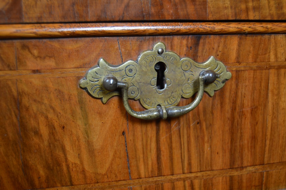 A Georgian walnut chest on stand with layered drawers, decorative brass drop handles, and carved cabriole legs. View II