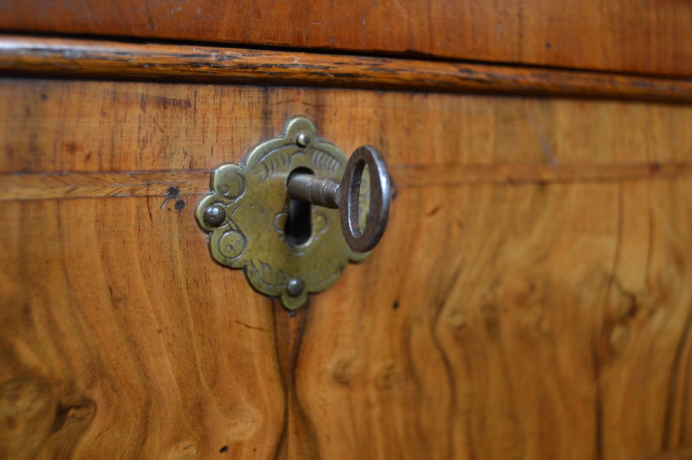 A Georgian walnut chest on stand with layered drawers, decorative brass drop handles, and carved cabriole legs. View III