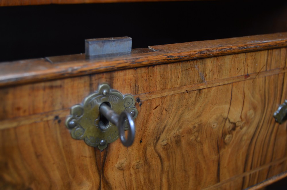 A Georgian walnut chest on stand with layered drawers, decorative brass drop handles, and carved cabriole legs. View V