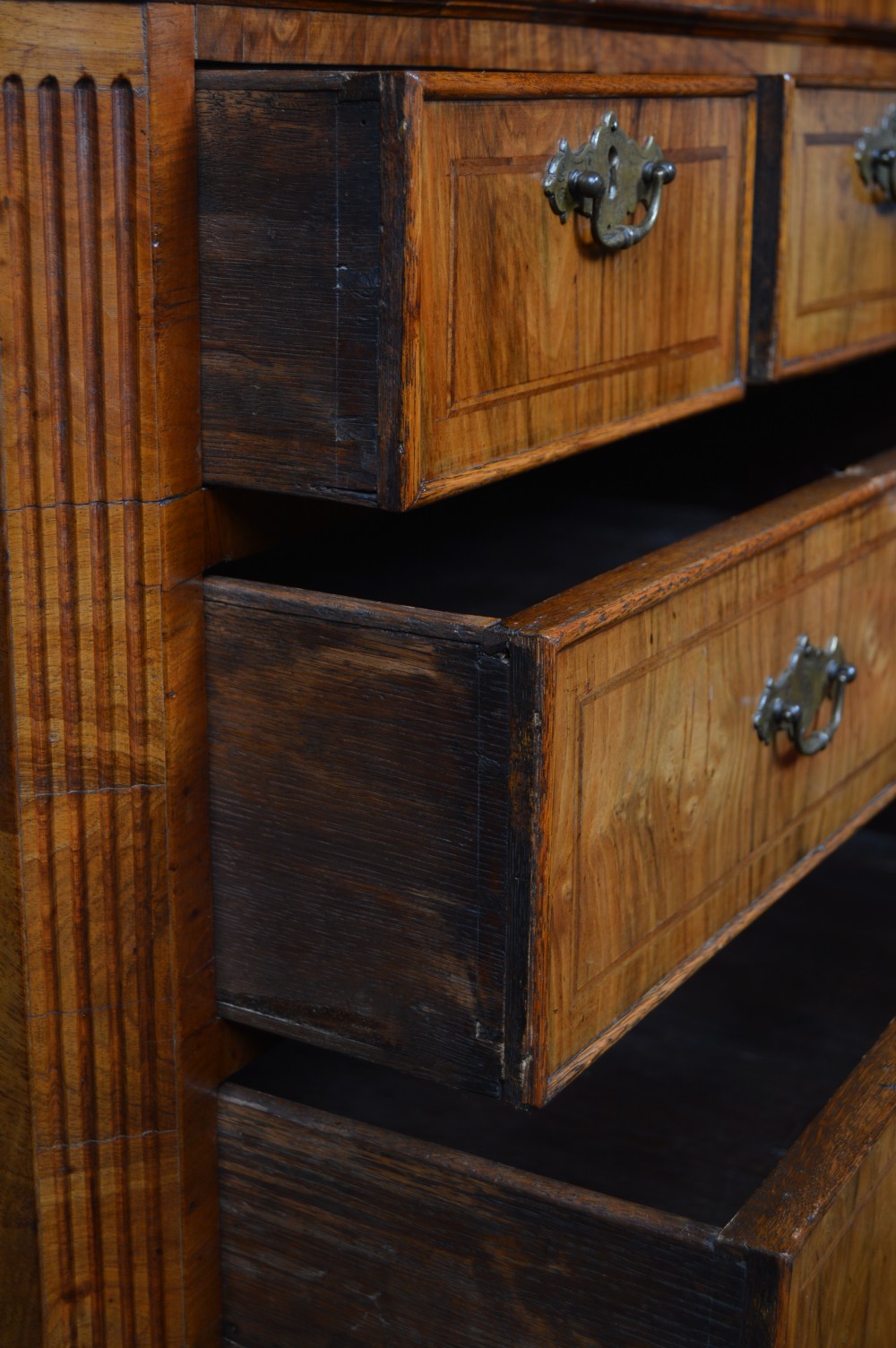A Georgian walnut chest on stand with layered drawers, decorative brass drop handles, and carved cabriole legs. View X
