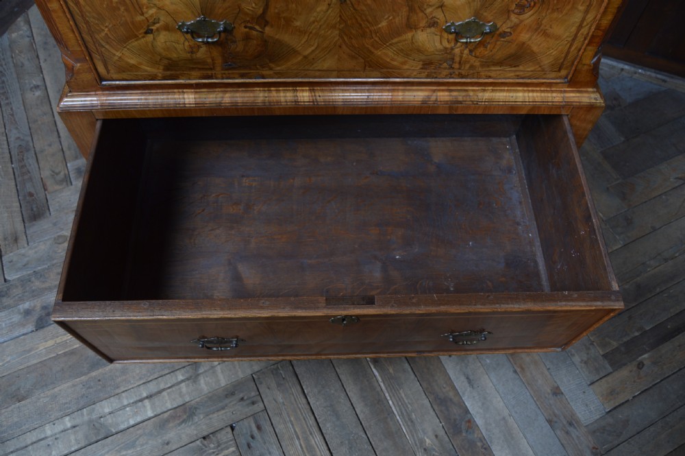 A Georgian walnut chest on stand with layered drawers, decorative brass drop handles, and carved cabriole legs. View XI
