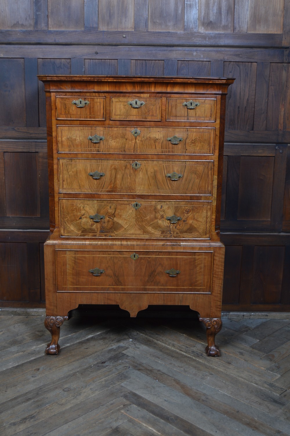 A Georgian walnut chest on stand with layered drawers, decorative brass drop handles, and carved cabriole legs. View XII