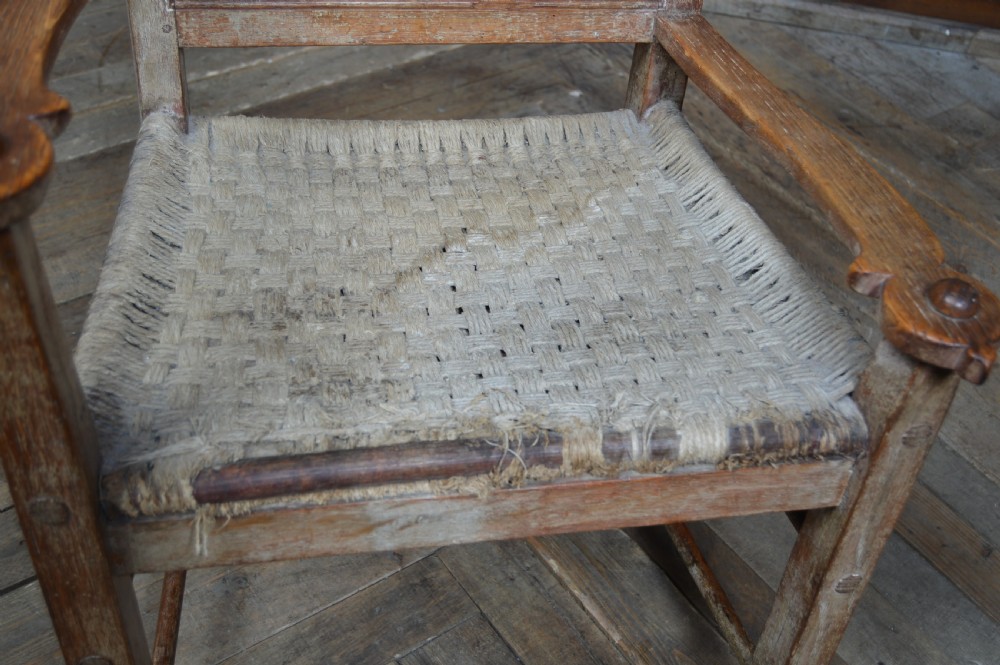 An antique Scottish oak crofter armchair featuring vertical back slats, a carved top rail, exposed wooden pegs, and a woven rush seat. View III