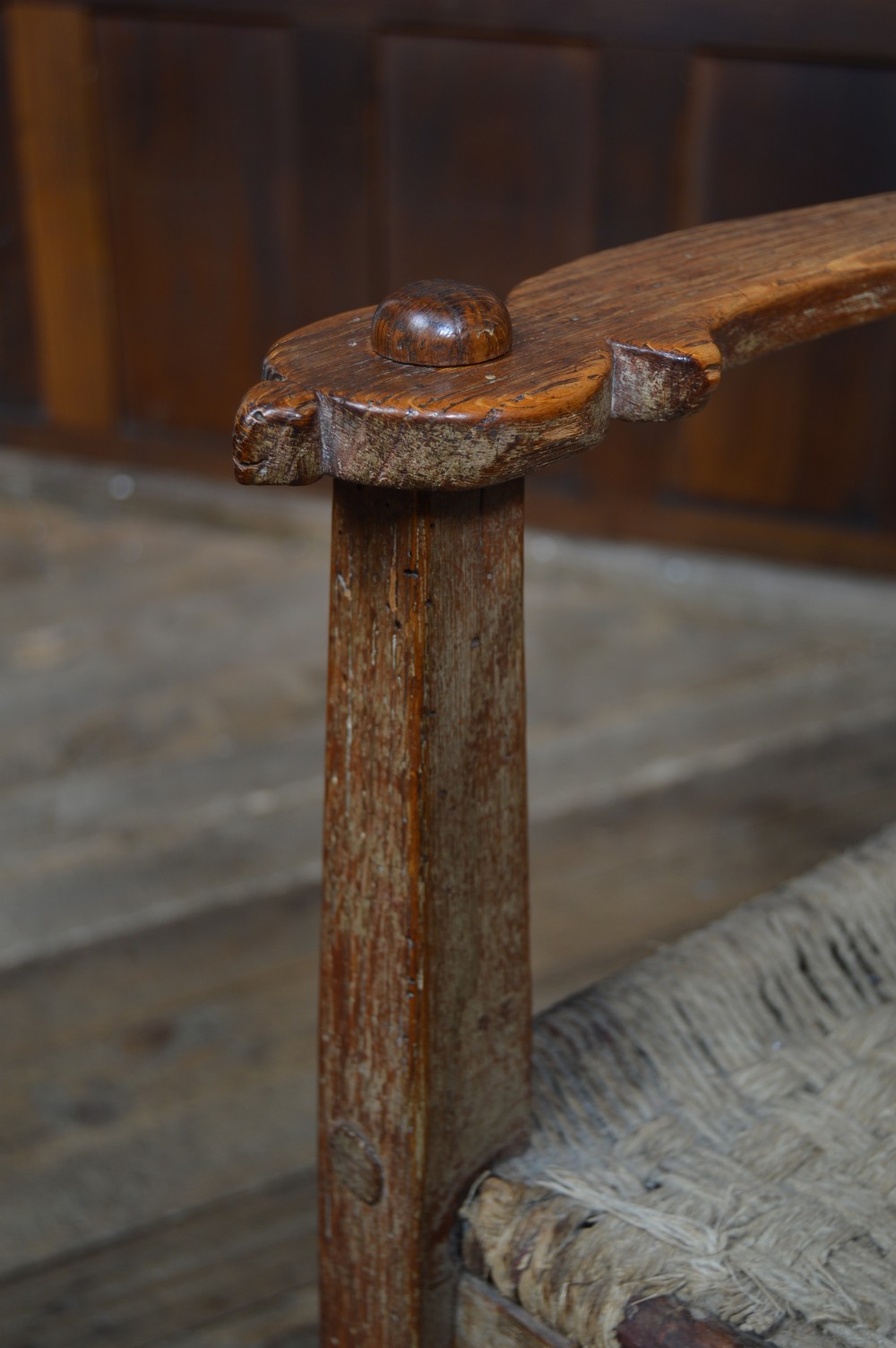 An antique Scottish oak crofter armchair featuring vertical back slats, a carved top rail, exposed wooden pegs, and a woven rush seat. View XIV