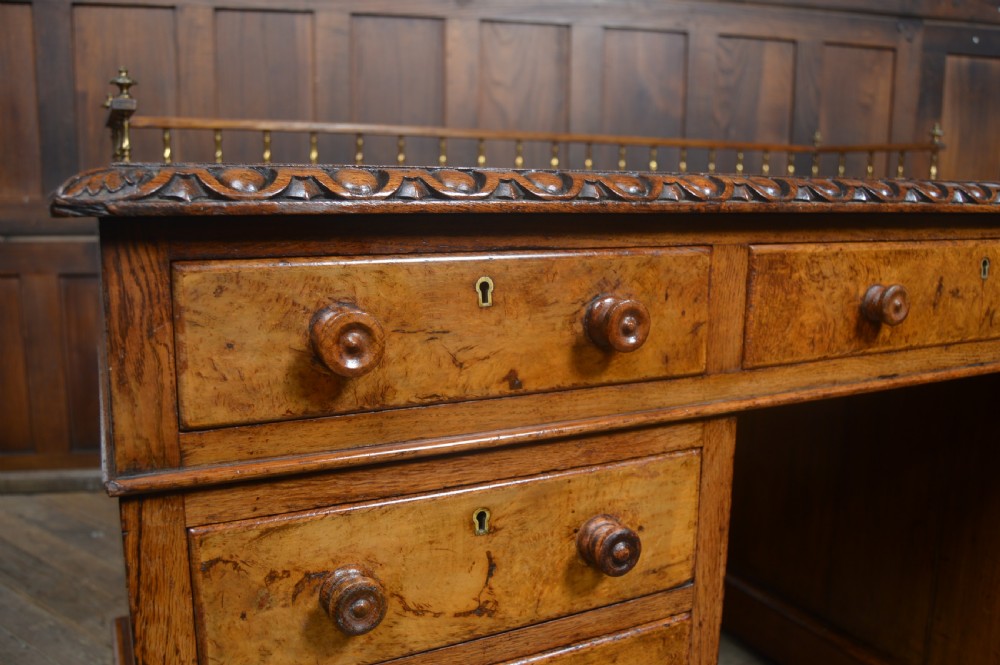 Victorian warm brown oak pedestal writing desk with a green leather inset top, brass gallery rail, and nine drawers. View III