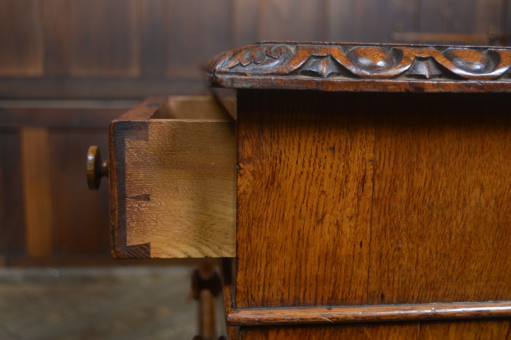 Victorian warm brown oak pedestal writing desk with a green leather inset top, brass gallery rail, and nine drawers. View XIV