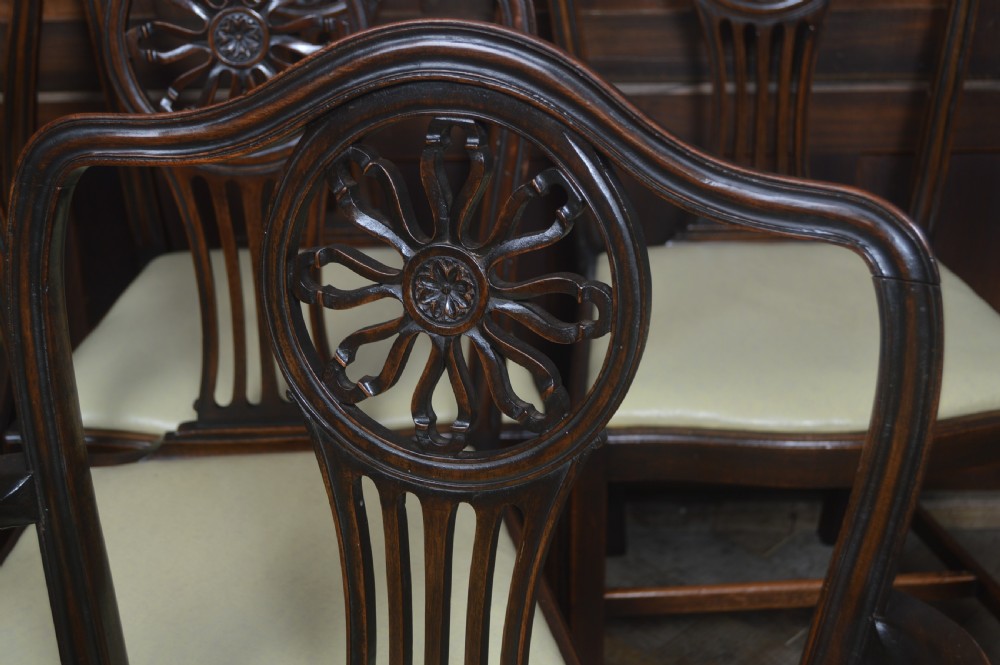 A set of eight dark mahogany Edwardian dining chairs with carved rosette back splats and cream upholstered seats, including two carvers. View IV