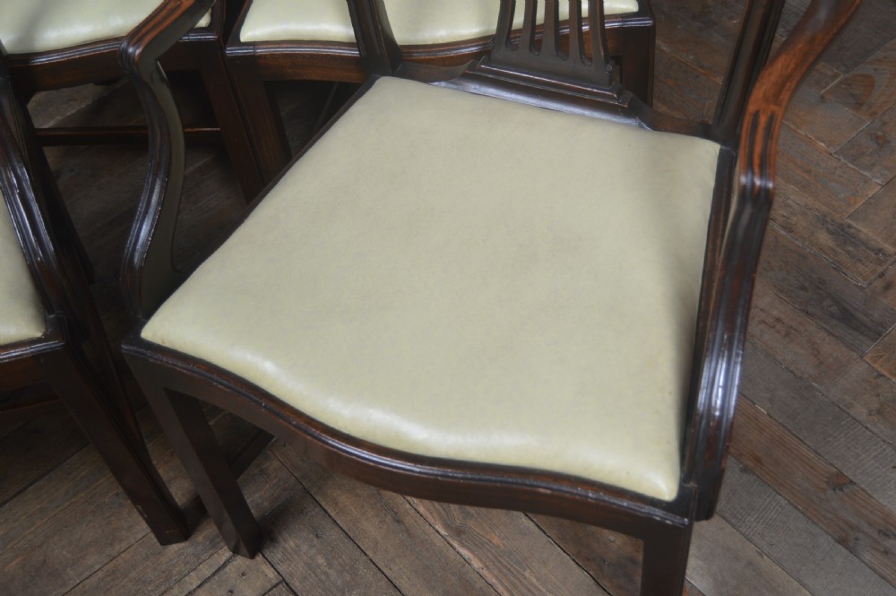 A set of eight dark mahogany Edwardian dining chairs with carved rosette back splats and cream upholstered seats, including two carvers. View V